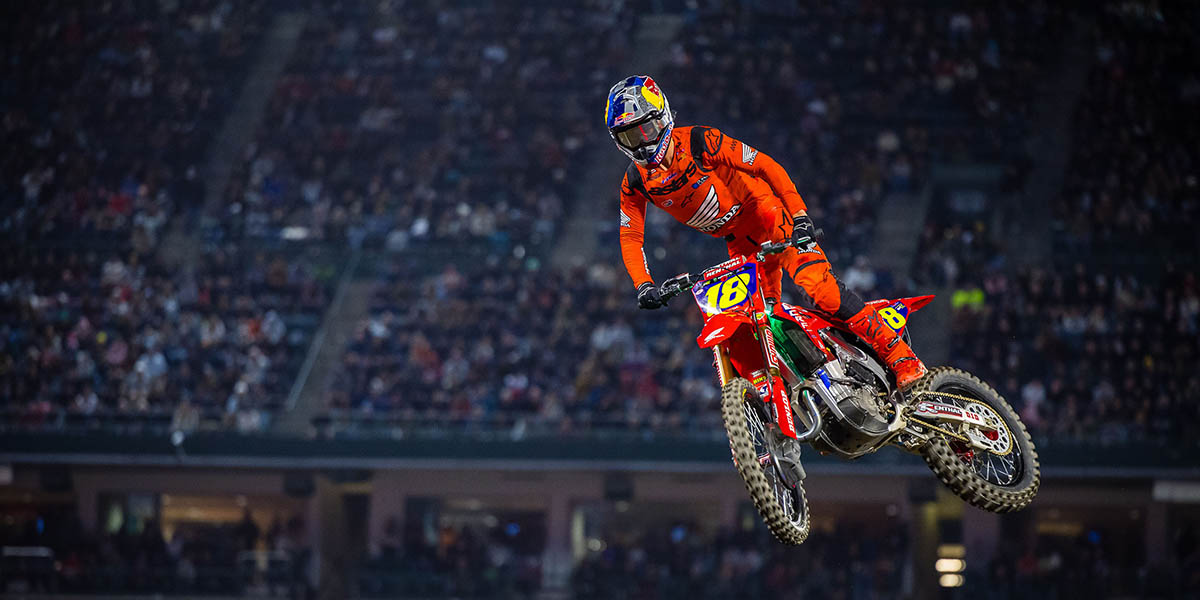 Supercross rider jumping in a packed stadium at night